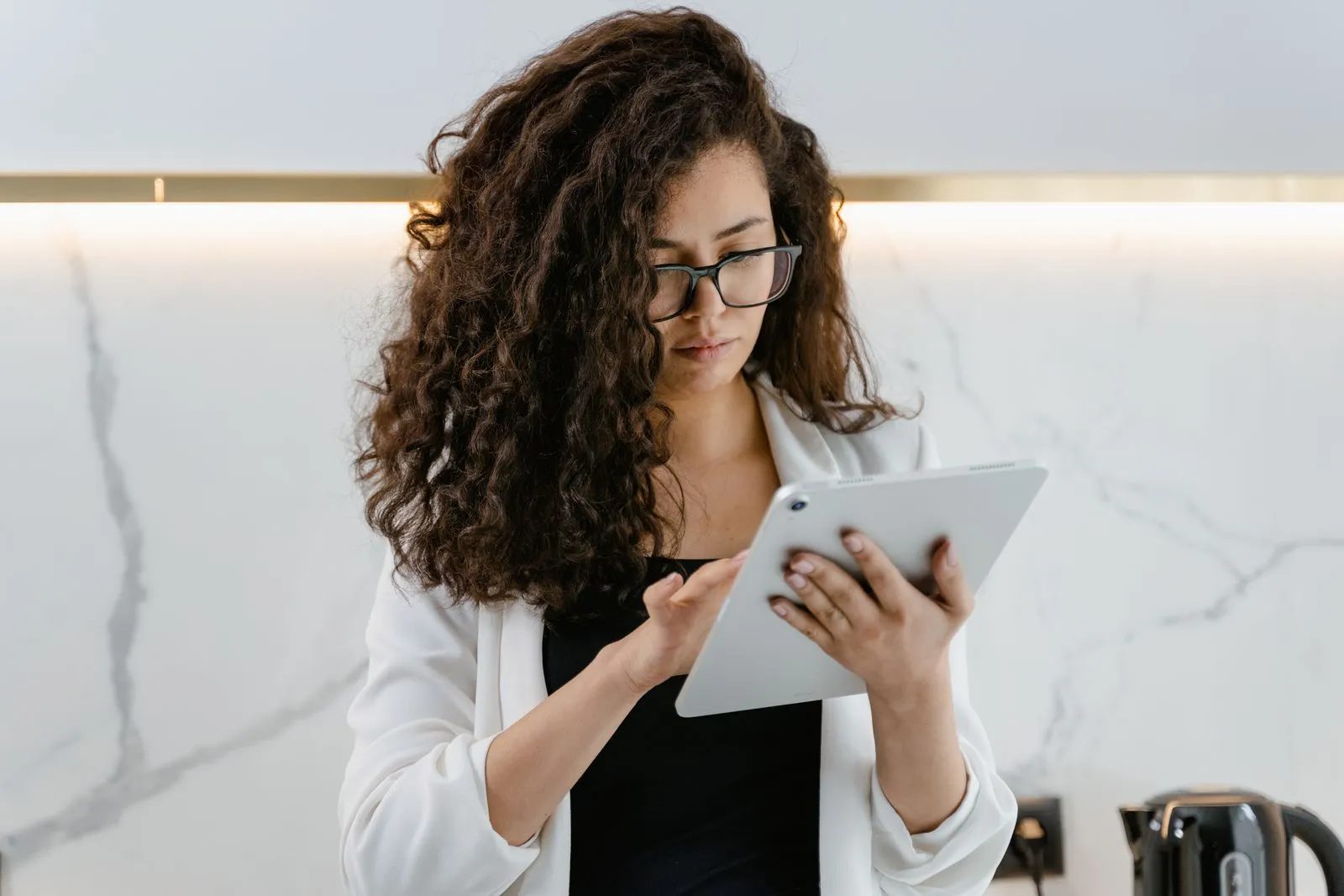 An appraiser in business-casual clothes reviewing notes on a tablet in a home’s kitchen