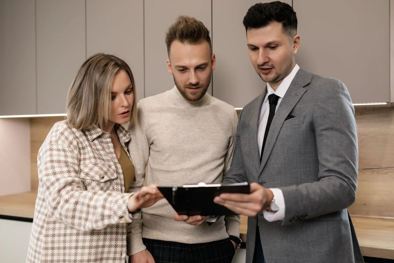 An experienced professional reviews notes on a clipboard with two colleagues in a kitchen